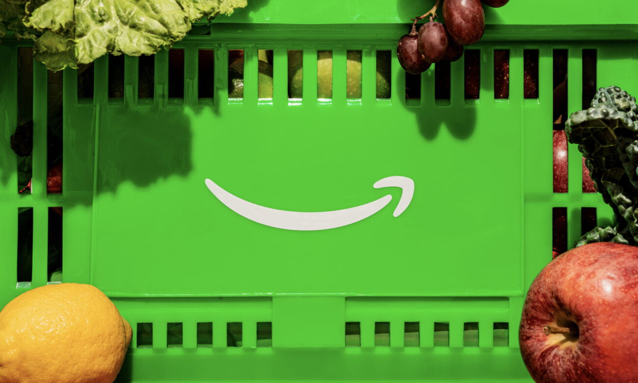 Caixa verde da Amazon Fresh com o sorriso branco ao centro, rodeada de frutas